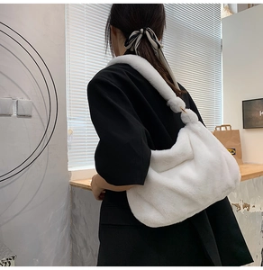 Nahaufnahme der weichen weißen Plüsch-Schultertasche aus Kunstpelz auf schwarzem Blazer
