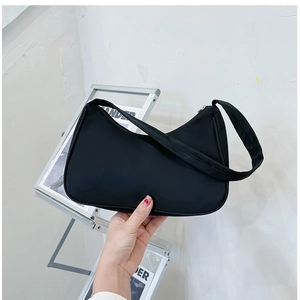 Detail of minimalist black nylon crescent bag showing texture and hand-held strap capacity