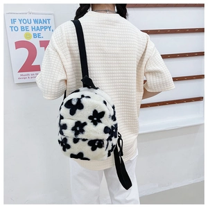 Détail d'un sac à dos en peluche à fleurs noires et blanches avec bretelles noires