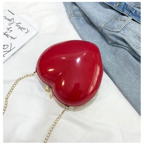 Detail of red heart-shaped patent leather mini bag with gold chain and dual zipper closure
