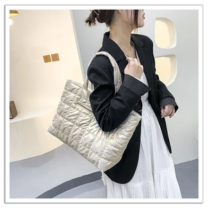 Elegante borsa tote trapuntata color oro champagne indossata da una modella di moda