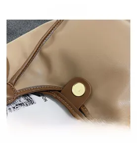 Vue macro détaillée du fermoir magnétique doré sur le sac à main en cuir grainé de couleur kaki