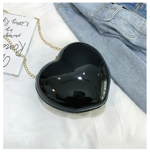 Close-up of heart-shaped black patent leather bag with gold chain strap detail