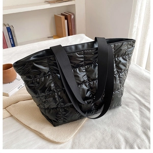 Detail shot of large capacity black quilted tote bag with soft padded down fabric texture