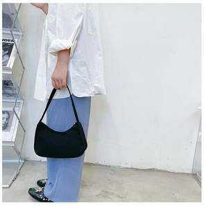 Detail shot of a minimalist black nylon crescent hobo bag with a smooth zipper closure