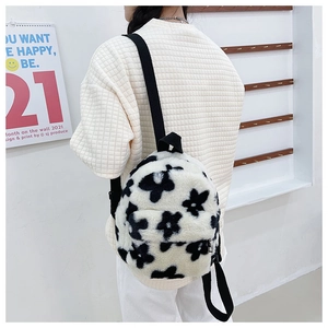 Détails de la texture pelucheuse et du motif de fleurs noires sur le sac à dos blanc doux