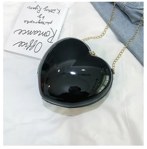 Detailed view of a heart-shaped black leather mini bag with a fine gold chain strap