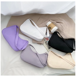 Flat lay of minimalist nylon hobo bags in five different colors with fashion props