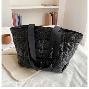 Detail of black quilted puffer tote bag with spacious capacity and fabric strap