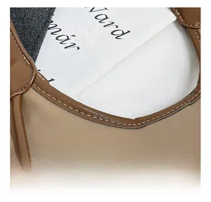 Détail montrant les coutures précises et le grain de cuir litchi sur le sac en cuir marron