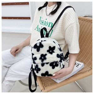 Détail de la texture douce en peluche à fleurs noires et blanches du petit sac à dos