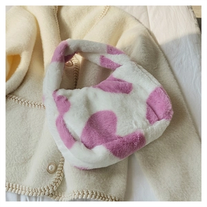 Vue détaillée d'un sac seau en fausse fourrure motif vache sur un fond en maille