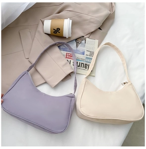 Detail view of purple and beige nylon crescent bags on a beige suit with a coffee cup