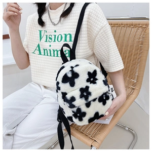 Détail d'un sac à dos en peluche douce avec motif floral noir et blanc et bretelles