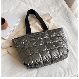 Detailed top view of silver quilted tote bag with black straps on aesthetic soft fabric