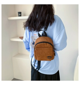 Brauner Mini-Rucksack aus Cord am Model im Vintage-Stil mit eleganten Metallhaken
