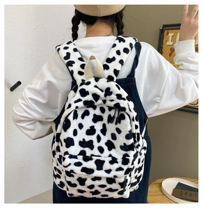 Vista posteriore di uno zaino in peluche con stampa mucca indossato da una modella