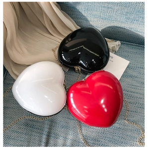 Macro view of heart-shaped mini chain bags in glossy finish and gold metal zippers