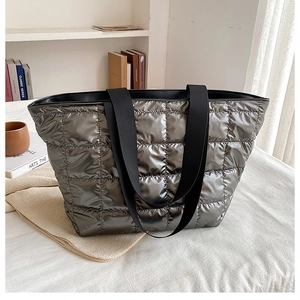 Close-up of quilted metallic tote bag with puffer padding and black woven straps