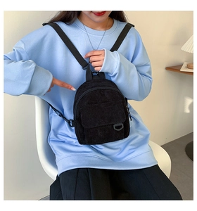 Detailansicht des Mini-Rucksacks aus schwarzem Cord mit feiner Textur und Fronttasche