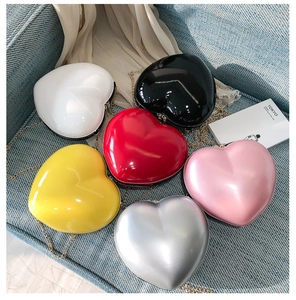 Flat lay of heart-shaped hard shell mini chain bags in six vibrant glossy colors