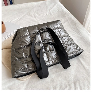 Detail showing metallic silver quilted texture and black straps of the tote bag