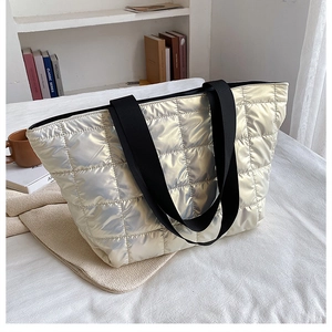 Detailed macro view of quilted silver down tote bag with black nylon straps and metallic finish