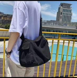 Detail view of durable black canvas messenger bag featuring a secure buckle and side pocket