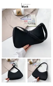 Detail view of a black nylon crescent shoulder bag featuring a smooth metal zipper closure