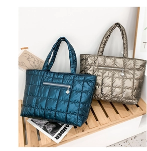 Dettaglio di borse tote trapuntate blu e oro con tasche a zip e manici imbottiti morbidi