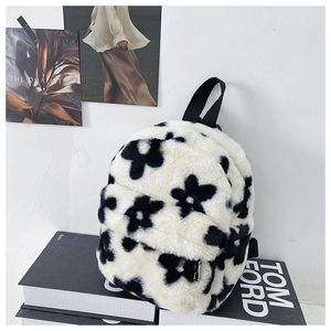 Détail d'un sac à dos en peluche douce avec motif floral noir et sangles en nylon sur livre