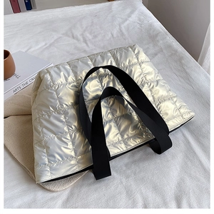 Detail view of large quilted silver tote bag with quilted nylon texture and black handles