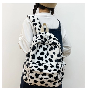Vista posteriore della modella con zaino in peluche bianco e nero con stampa mucca