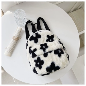 Détail d'un sac à dos en peluche douce avec motif floral noir et blanc et fermeture éclair