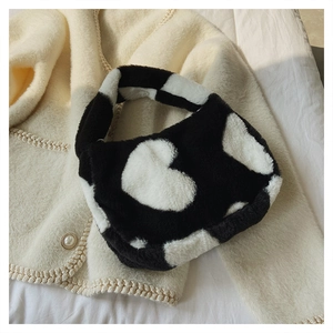 Détail du mini sac seau en fausse fourrure motif vache avec cœur sur fond de tricot