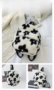 Détail d'un sac à dos en peluche à fleurs avec motifs noirs et fermeture éclair en métal
