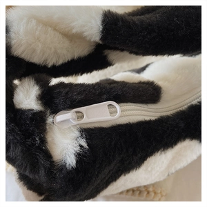 Gros plan de la fermeture éclair sur ce sac à main doux en peluche à motif de vache