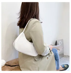 White nylon shoulder bag shown as a sleek baguette style on a person's shoulder