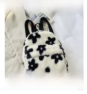 Détail d'un sac à dos en peluche à fleurs noir et blanc avec poche zippée et texture douce