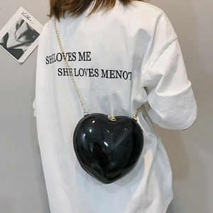 Detail of a chic heart-shaped crossbody bag in black leather with a gold chain strap