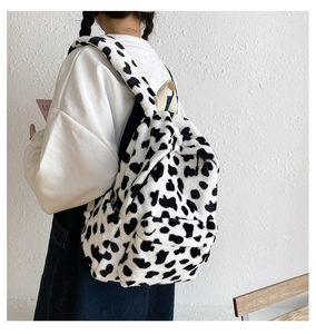 Dettaglio dello zaino in peluche con motivo a mucca bianco e nero e manico beige morbido