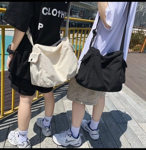 Detail view of large canvas crossbody bags in black and white with functional side pockets