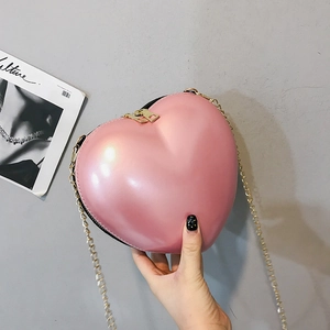 Detail of pearlescent pink heart-shaped bag with gold chain strap and double zipper