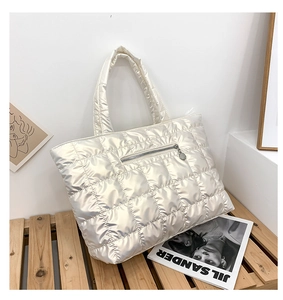 Detail van gewatteerde puffer shopper in champagnegoud met gevoerde handvatten en rits