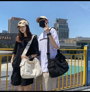 Close-up of black and white large-capacity washed canvas messenger bags for couples