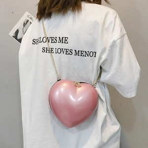 Detailed view of pink heart-shaped mini crossbody bag with golden chain and pearl finish
