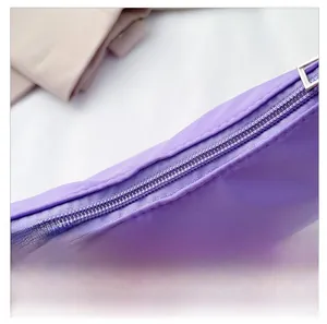 Detail view of the smooth silver metal zipper on a purple nylon minimalist shoulder bag