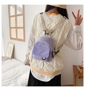 Detailansicht des lila Cord-Minirucksacks mit verstellbaren beigen Trägern am Model