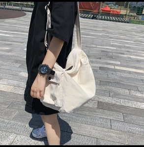Outdoor street shot of off-white canvas crossbody bag with side cargo pocket