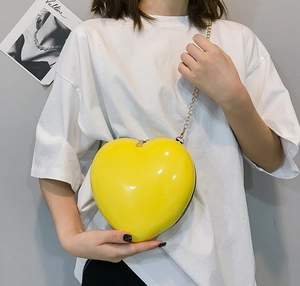 Modern heart shaped mini bag in bright yellow with gold chain strap on model